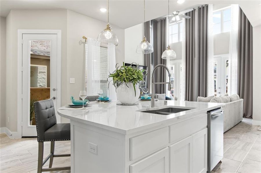 Kitchen featuring white cabinets, dishwasher, a kitchen breakfast bar, hanging light fixtures, and sink