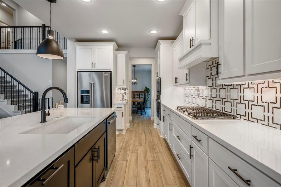 You will love the details of this kitchen! It features crown molding, a large single basin sink with sleek black faucet, black cabinet hardware, walk-in pantry, splendid textured backsplash, LED overhead lighting, contrasting cabinets, and black pendant lights.