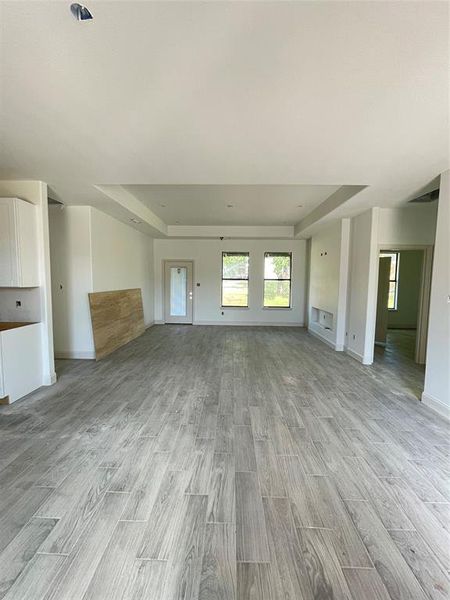 Unfurnished living room with light hardwood / wood-style floors and a tray ceiling