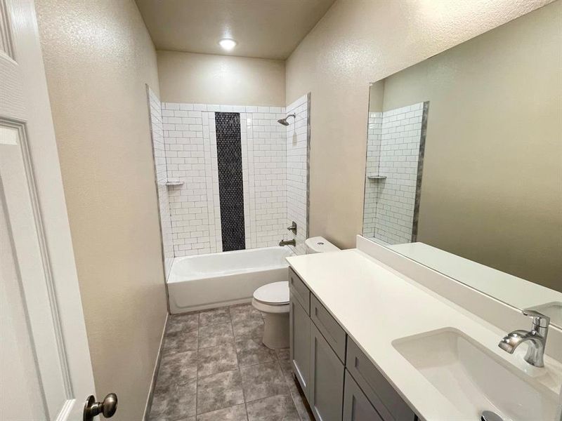 Full bathroom with toilet, tiled shower / bath, vanity, and tile patterned flooring