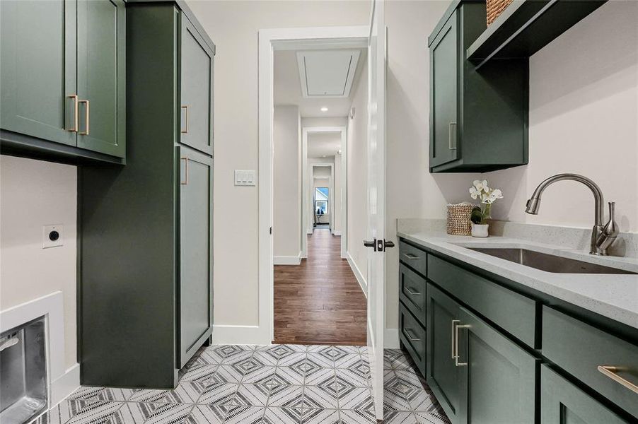 Laundry with built in storage, sink, quartz counters, tile floors