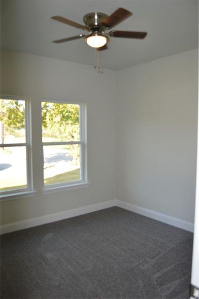 Carpeted bedroom featuring ceiling fan and a healthy amount of sunlight