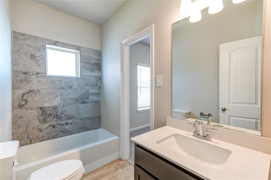 This secondary bath features modern fixtures and a functional layout. It includes a sleek vanity with ample storage, a spacious mirror, and a well-designed shower or tub area. The room is complemented by neutral colors and efficient lighting, offering both style and convenience.