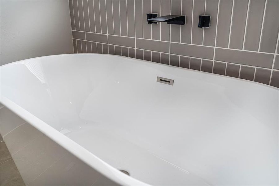 Soak-in bathtub complemented by the convenience of a wall-mount tub filler for added elegance and functionality.