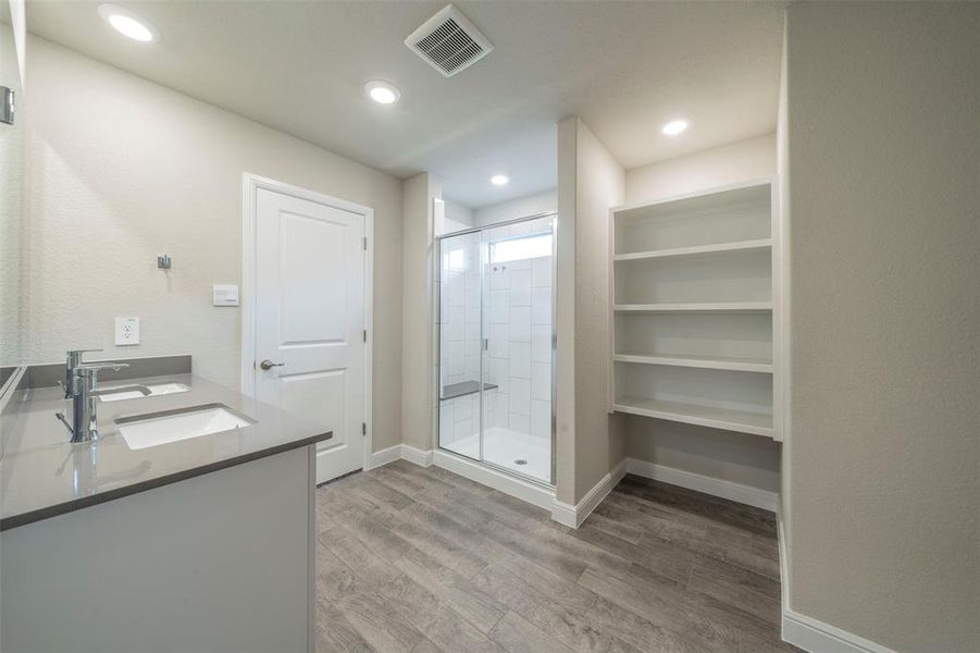 Primary bathroom has extra storage shelves and large walk in shower with bench.