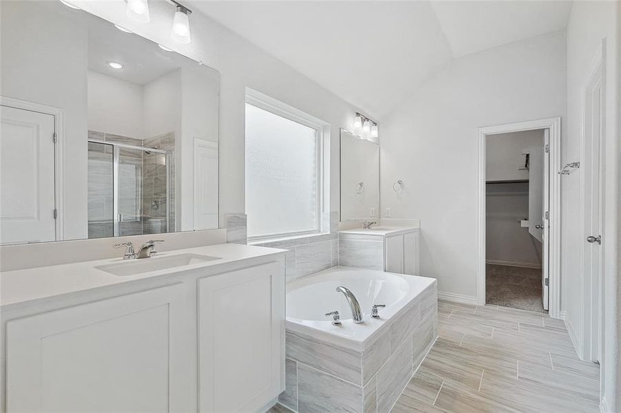 Bathroom featuring vaulted ceiling, independent shower and bath, and vanity