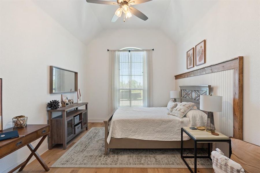 Bedroom with ceiling fan, vaulted ceiling, and wood-type flooring