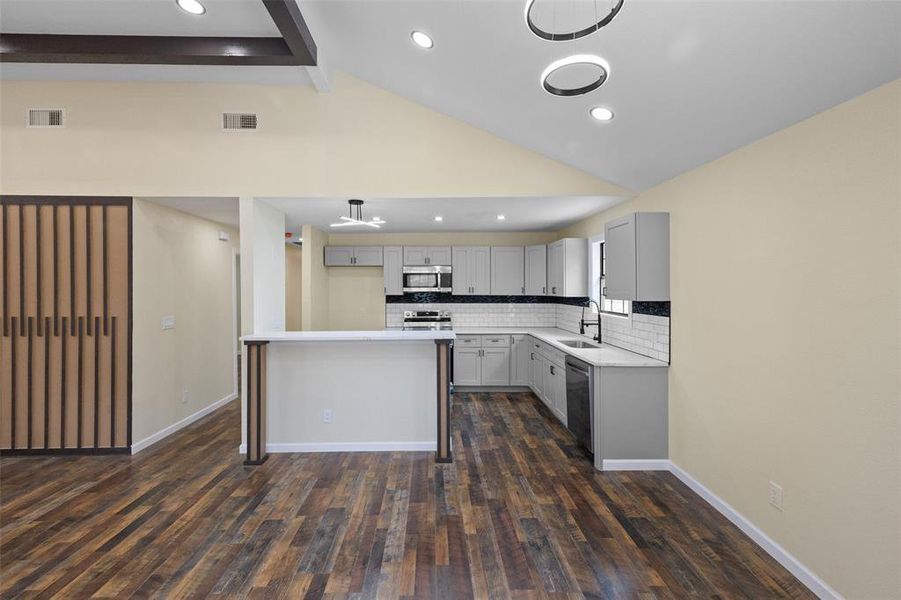 Kitchen featuring dark hardwood / wood-style floors, stainless steel appliances, beamed ceiling, and sink