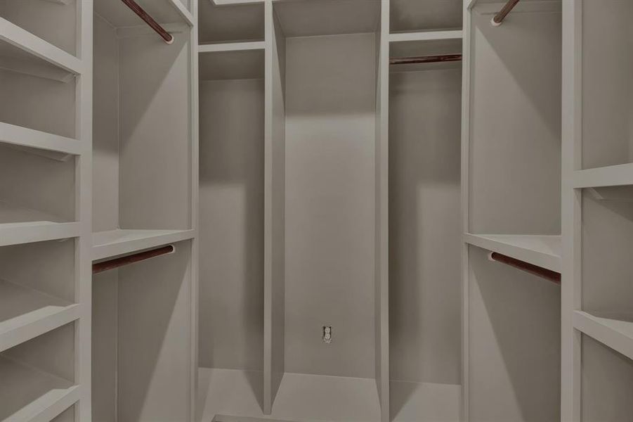 The primary bedroom offers two spacious walk-in closets with built-in shelves and hanging rods, offering ample storage for clothing and accessories.