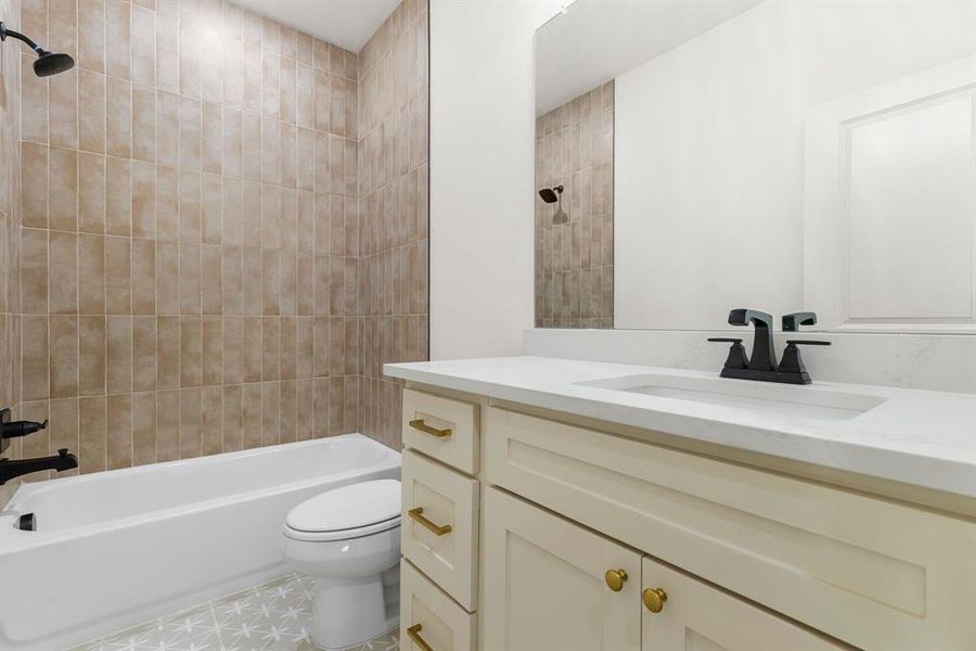 Full bathroom with vanity, tile patterned flooring, tiled shower / bath, and toilet