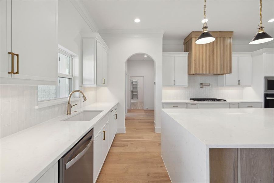 Kitchen featuring decorative light fixtures, white cabinetry, appliances with stainless steel finishes, and sink