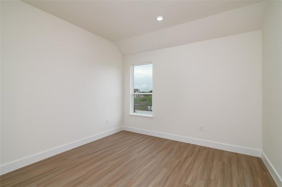 Empty room with light hardwood / wood-style flooring and lofted ceiling