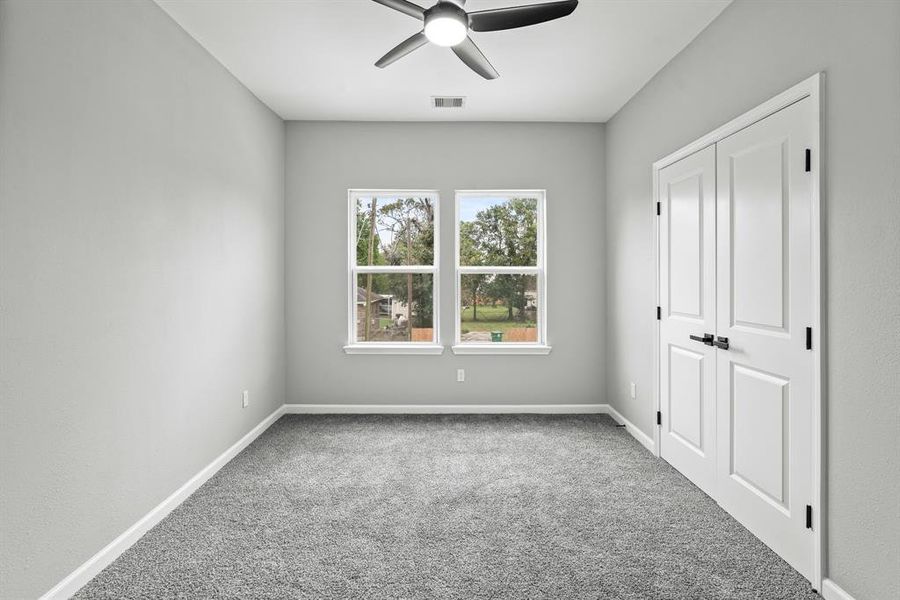 Secondary bedroom with plush carpet and ceiling fan.