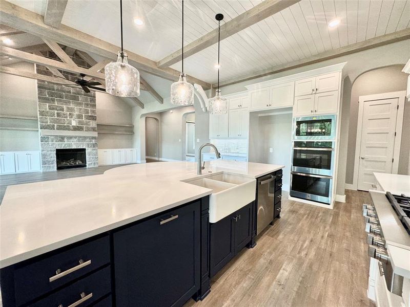 Kitchen featuring a fireplace, pendant lighting, white cabinetry, and light hardwood / wood-style floors