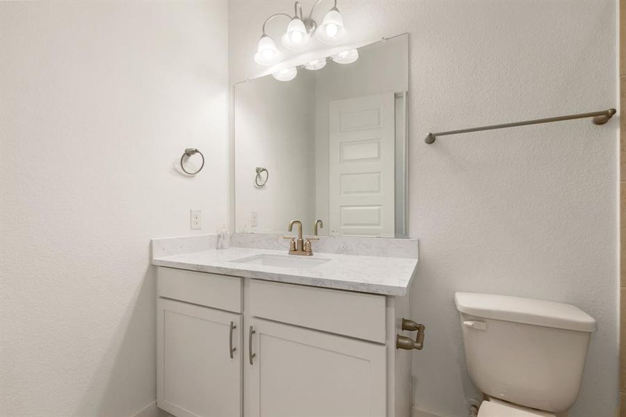 Secondary bath features tile flooring, bath/shower combo with tile surround, bright white cabinets, beautiful light countertops, mirror, sleek fixtures and modern finishes.