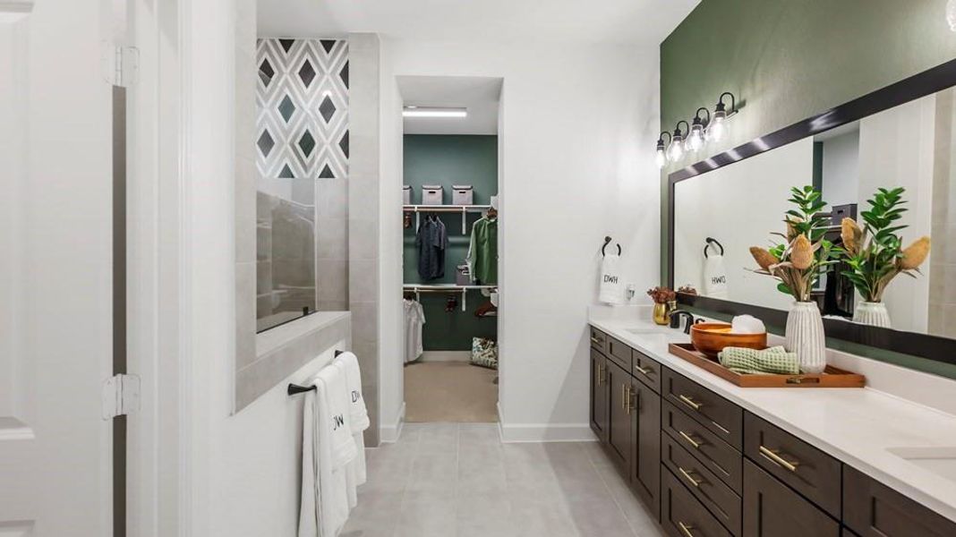 The Owner's bathroom features a double vanity with ample storage and a sleek quartz countertop. The overall design is modern and elegant, with a cohesive and stylish look