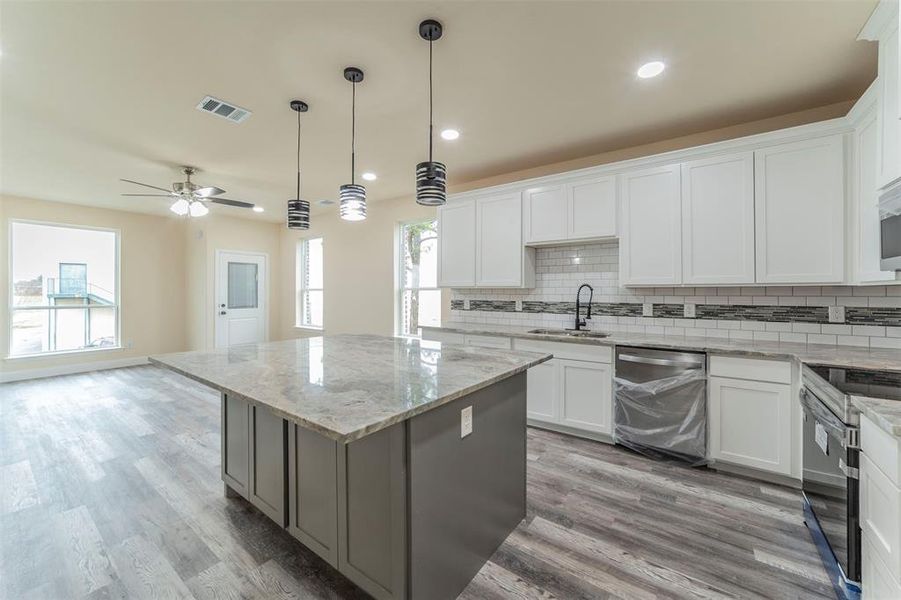 Kitchen featuring white cabinets, light hardwood / wood-style flooring, stainless steel appliances, ceiling fan, and a kitchen island