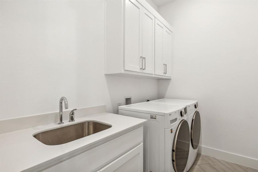 Washroom with cabinets, washer and clothes dryer, and sink