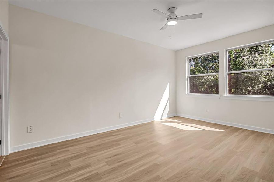 The bright primary bedroom is filled with natural light and large windows overlook the front of the home.