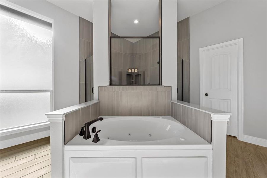 Bathroom with wood-type flooring and shower with separate bathtub