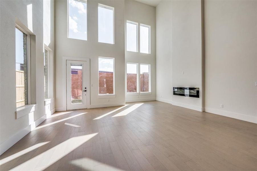 Unfurnished living room with a high ceiling, heating unit, and light hardwood / wood-style floors