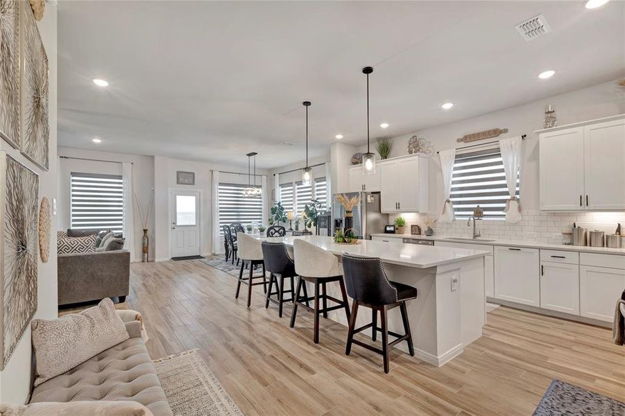 Gourmet Kitchen View - Oversized island with extra seating, custom Zebra blinds, bright and clean cabinets, and a backdoor leading to the stunning outdoor living area.