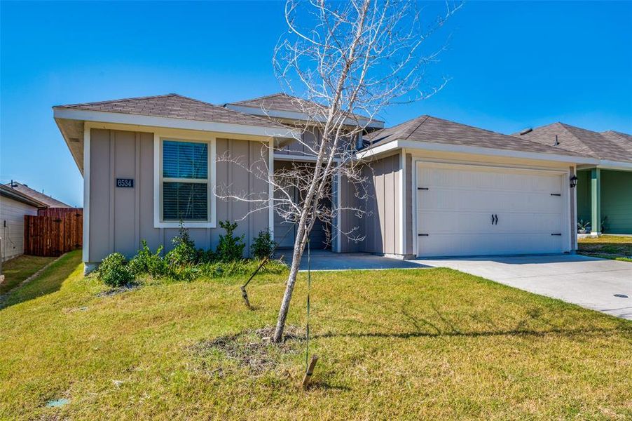 Ranch-style home featuring a garage and a front lawn