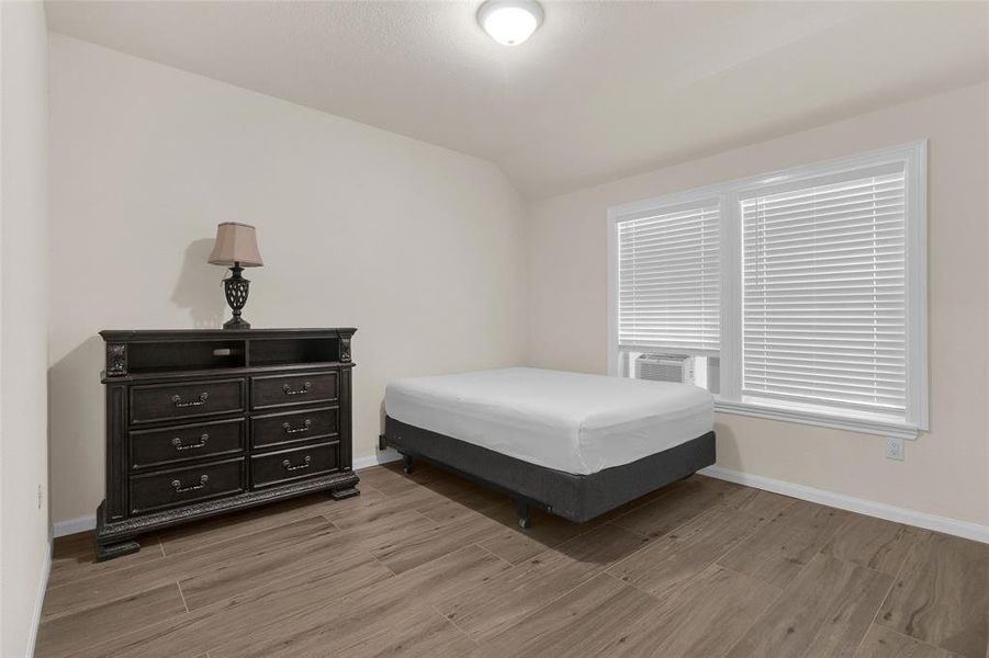 This is a neatly presented bedroom with a large window for natural light, a sizable closet. The room is painted in a light neutral color, offering a calm and versatile space.