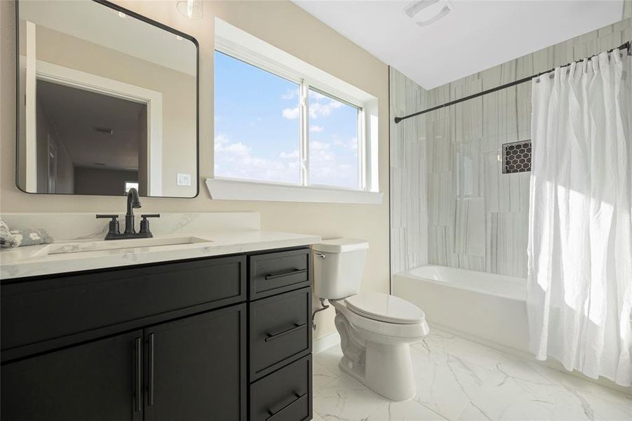 Full bathroom featuring vanity, shower / bath combo, and toilet