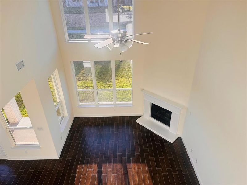 Unfurnished living room with a high ceiling, dark hardwood / wood-style floors, and ceiling fan