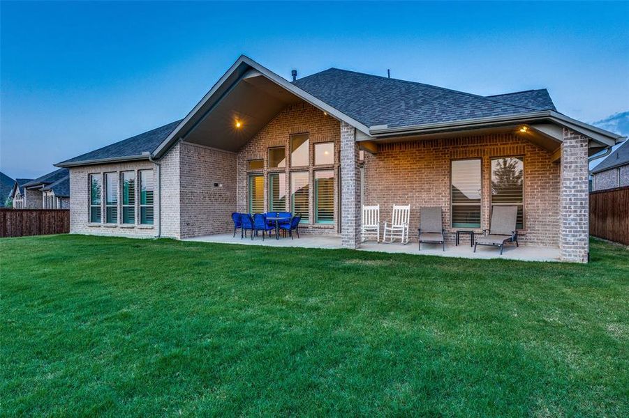 Back house at dusk with a patio and a yard