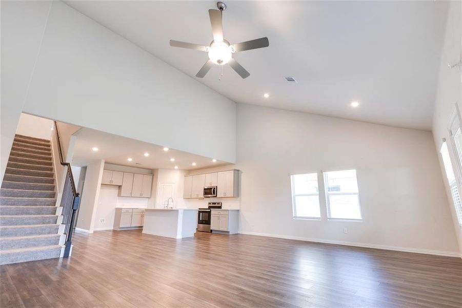Unfurnished living room with ceiling fan, light hardwood / wood-style flooring, and high vaulted ceiling