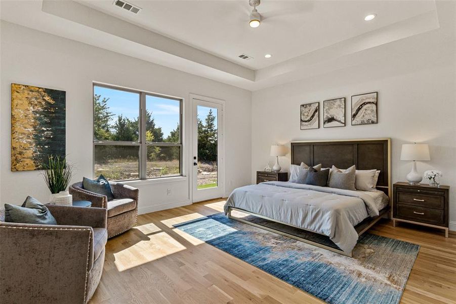 Bedroom featuring access to outside, a tray ceiling, and light wood-type flooring