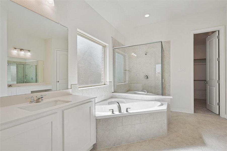 Bathroom with tile patterned flooring, separate shower and tub, and vanity