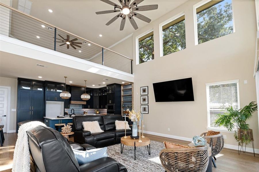 Living room featuring a towering ceiling, a wealth of natural light, and light hardwood / wood-style floors