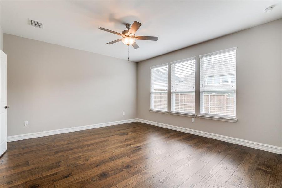 Empty room with ceiling fan and dark hardwood / wood-style floors