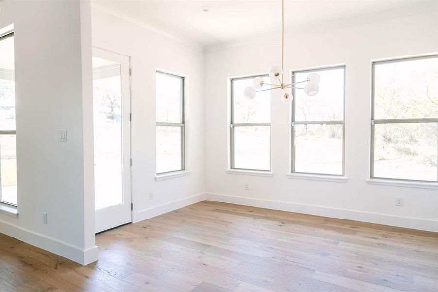 Unfurnished dining area featuring a notable chandelier, a healthy amount of sunlight, and light wood-type flooring