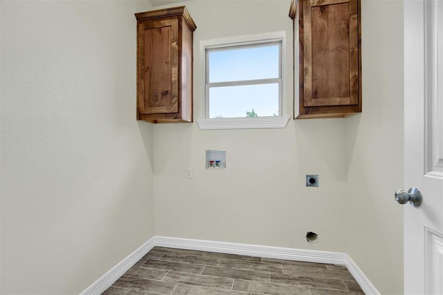 Clothes washing area with cabinets, hookup for an electric dryer, and washer hookup