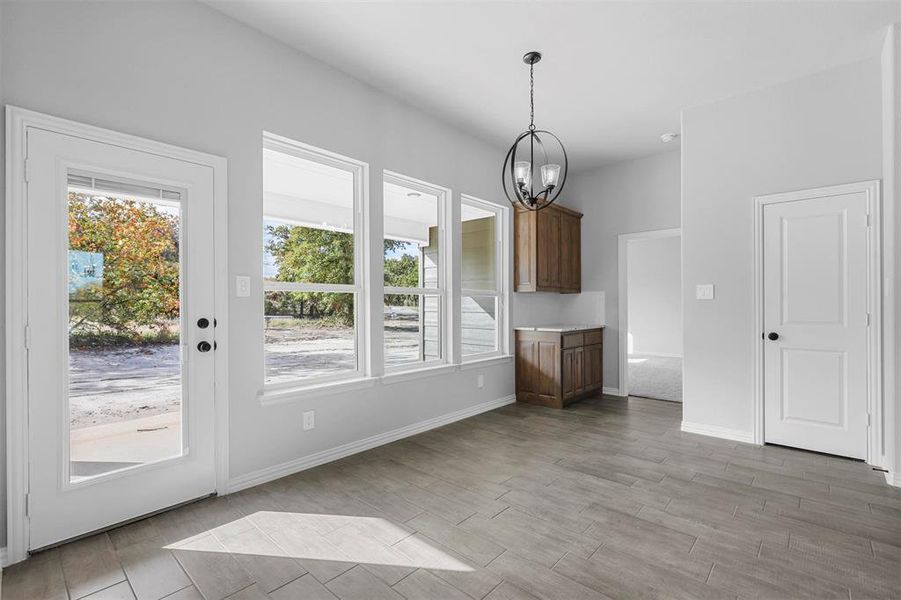 Unfurnished living room featuring wood-type flooring, a healthy amount of sunlight, and a chandelier