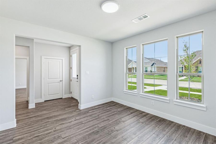 Empty room with a wealth of natural light and hardwood / wood-style floors