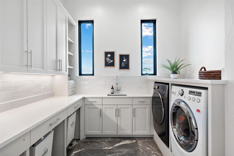 Laundry room featuring sink, dark tile patterned floors, and a healthy amount of sunlight