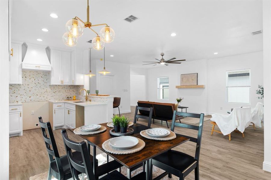 Dining space featuring ceiling fan with notable chandelier, light hardwood / wood-style flooring, and sink