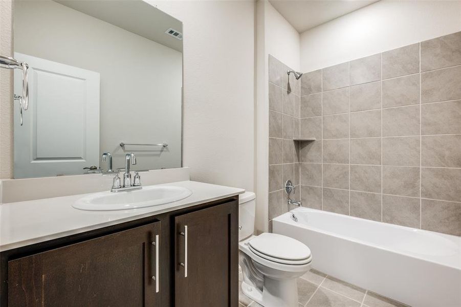 Full bathroom with vanity, toilet, tile patterned floors, and tiled shower / bath