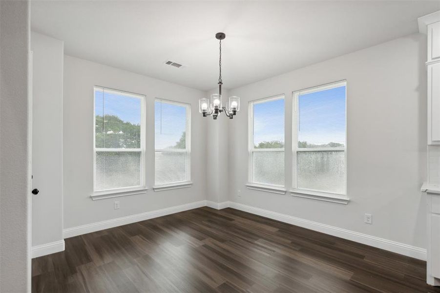 Empty room with dark wood-type flooring and a chandelier