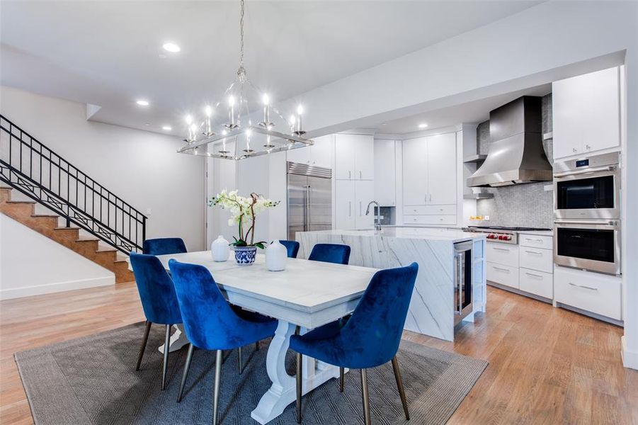 Dining room featuring sink, a notable chandelier, light hardwood / wood-style floors, and wine cooler