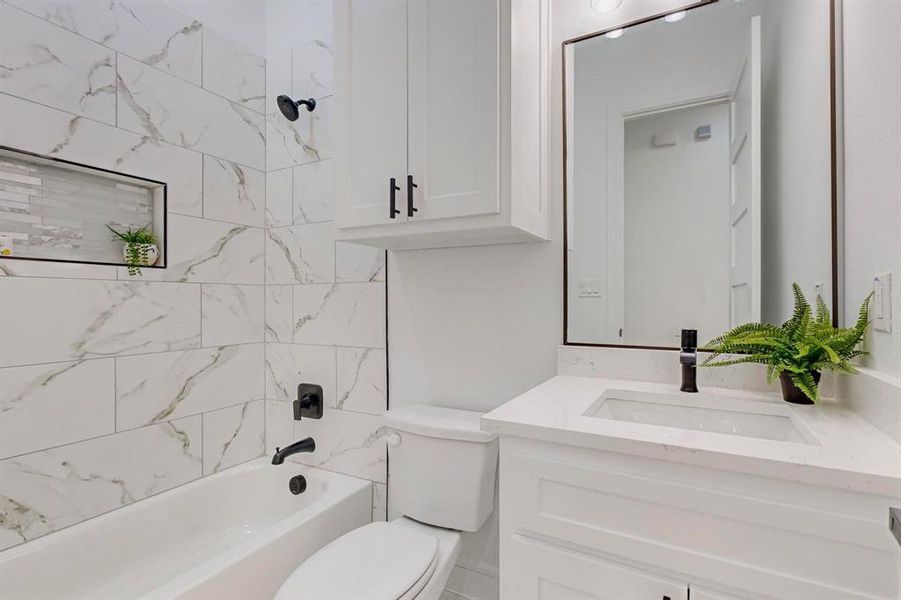 Full bathroom featuring tiled shower / bath combo, toilet, and vanity