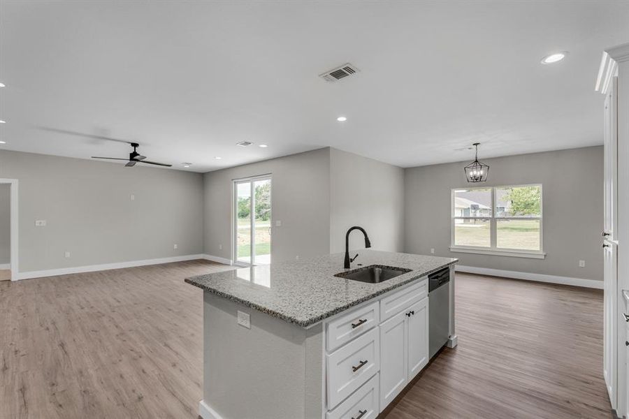 Kitchen featuring white cabinets, light wood-type flooring, sink, a kitchen island with sink, and stainless steel dishwasher