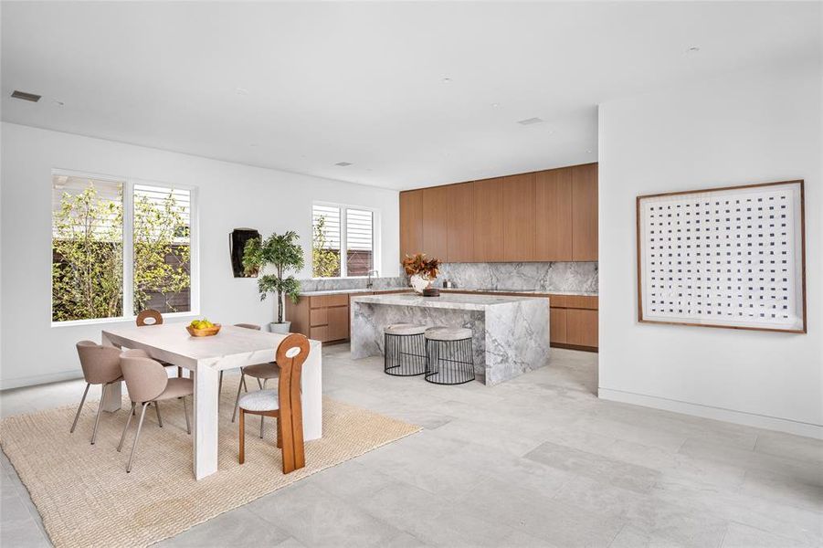 Grounded by elegant Moroccan limestone flooring, the dining and kitchen areas seamlessly flow together, while natural light pours in through large windows and highlights the modern design and attention to detail throughout.