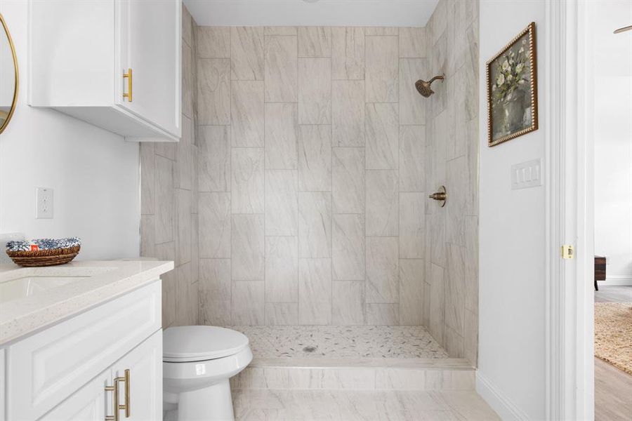 Bathroom featuring vanity, toilet, and a tile shower