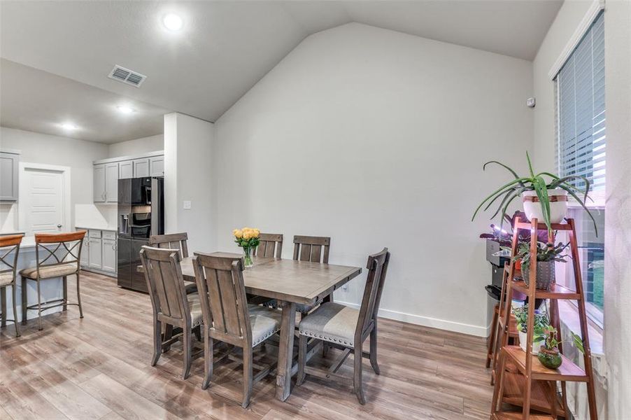 Dining room with light hardwood / wood-style floors and vaulted ceiling